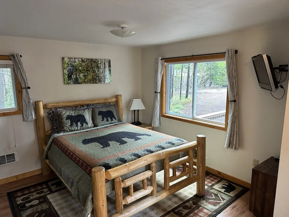 Lone Walker cabin bedroom with queen bed and forest views through large windows